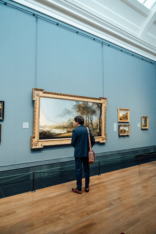 A man carrying a bag while viewing artwork in a modern art gallery