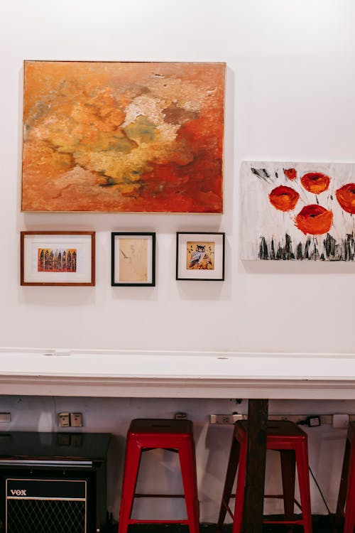 Another wall in an art gallery featuring multiple paintings arranged for exhibition