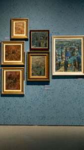 Multiple paintings displayed on a gallery wall in an exhibition setting