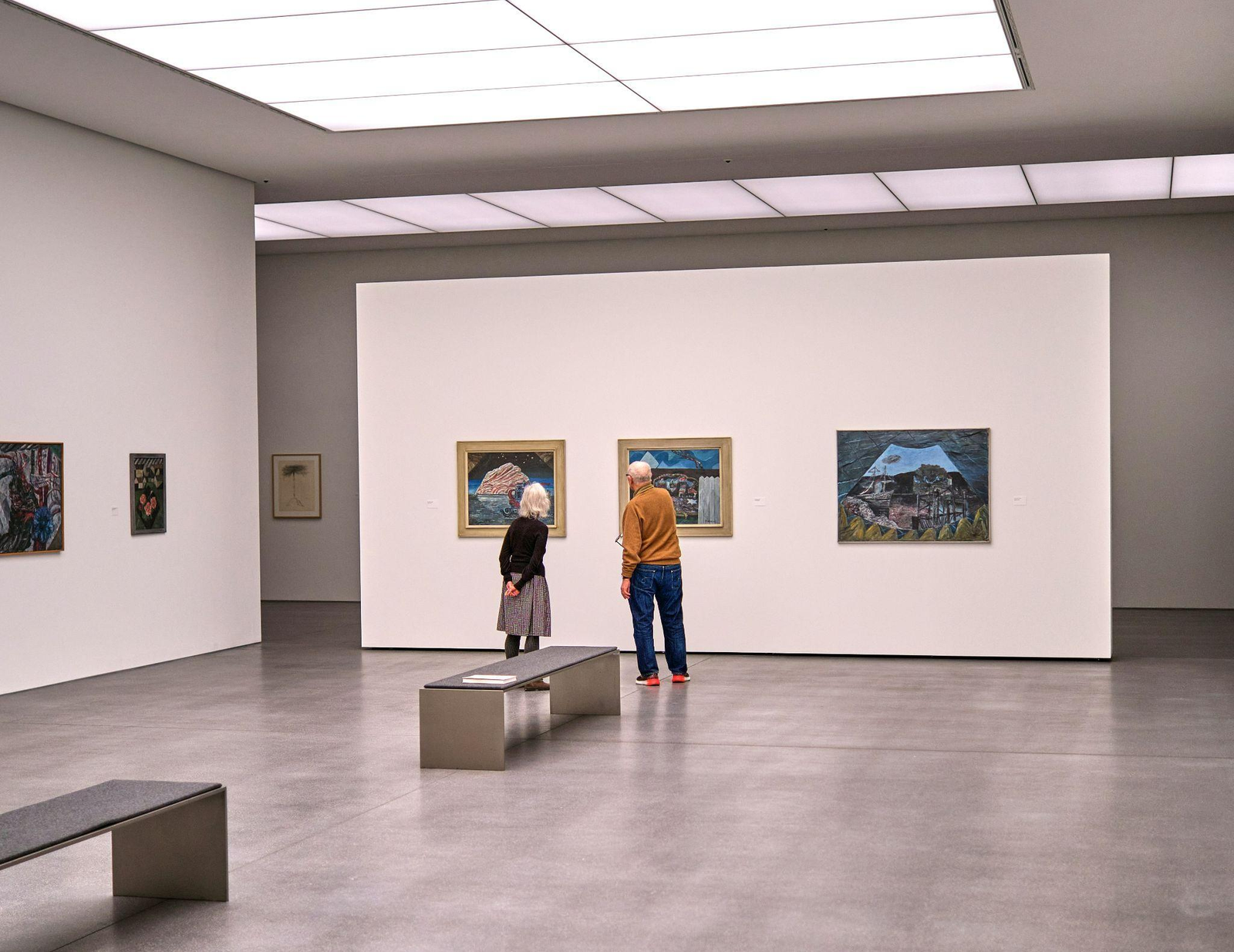 two people carefully inspecting an artwork